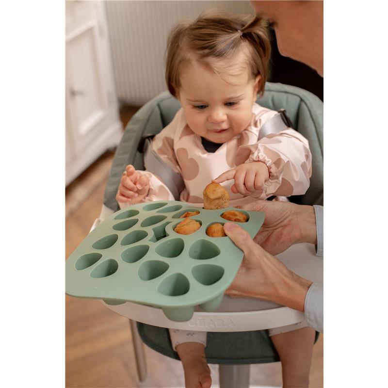Béaba Silicone Mini Multiportion Tray in sage green held by an adult, while a toddler reaches for food portions.