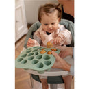 Béaba Silicone Mini Multiportion Tray in sage green held by an adult, while a toddler reaches for food portions.