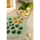 Béaba Silicone Mini Multiportion Tray in sage green with several portions filled with orange puree, surrounded by chopped zucchini and mint.