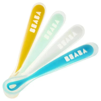 Set of four Beaba silicone spoons in yellow, mint green, white, and blue, designed for feeding infants.