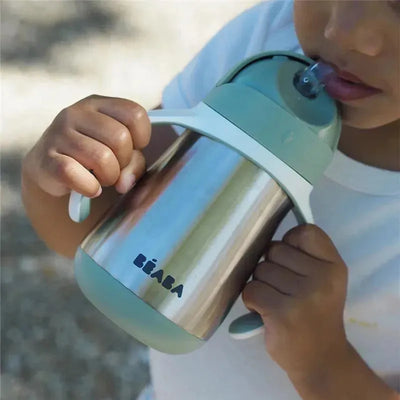 Stainless steel straw sippy cup by Béaba in sage color, held by a child, designed for easy drinking.