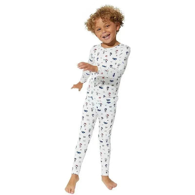Baby boy wearing a white pirate-themed long sleeve shirt and pants pajama set, smiling and posing playfully.