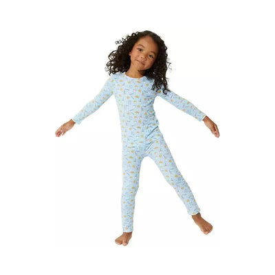 Blue two-piece pajama set featuring milk and cookie patterns, worn by a smiling girl with curly hair.