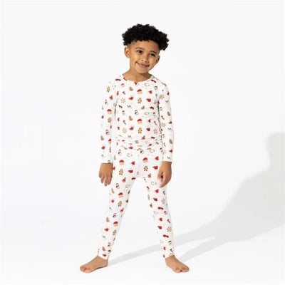 Two-piece bamboo pajamas for kids featuring Christmas cookie designs, worn by a smiling child with curly hair.