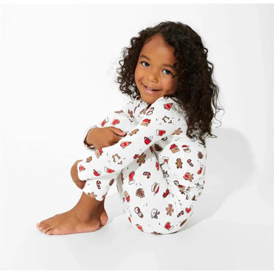 Bamboo pajamas for kids featuring a white base with colorful Christmas cookie patterns, modeled by a smiling girl.