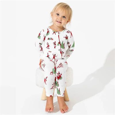 Bamboo Christmas pajamas featuring festive elf and holiday designs, worn by a smiling child sitting on a stool.