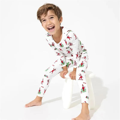 Boy laughing while wearing Bellabu Bear Elf On The Shelf bamboo pajamas with festive patterns on a white background.