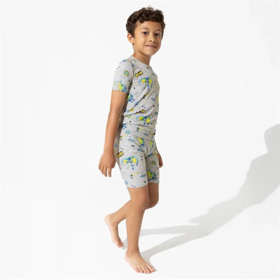 Toddler boy wearing a gray Batman-themed bamboo short set, smiling while walking barefoot.