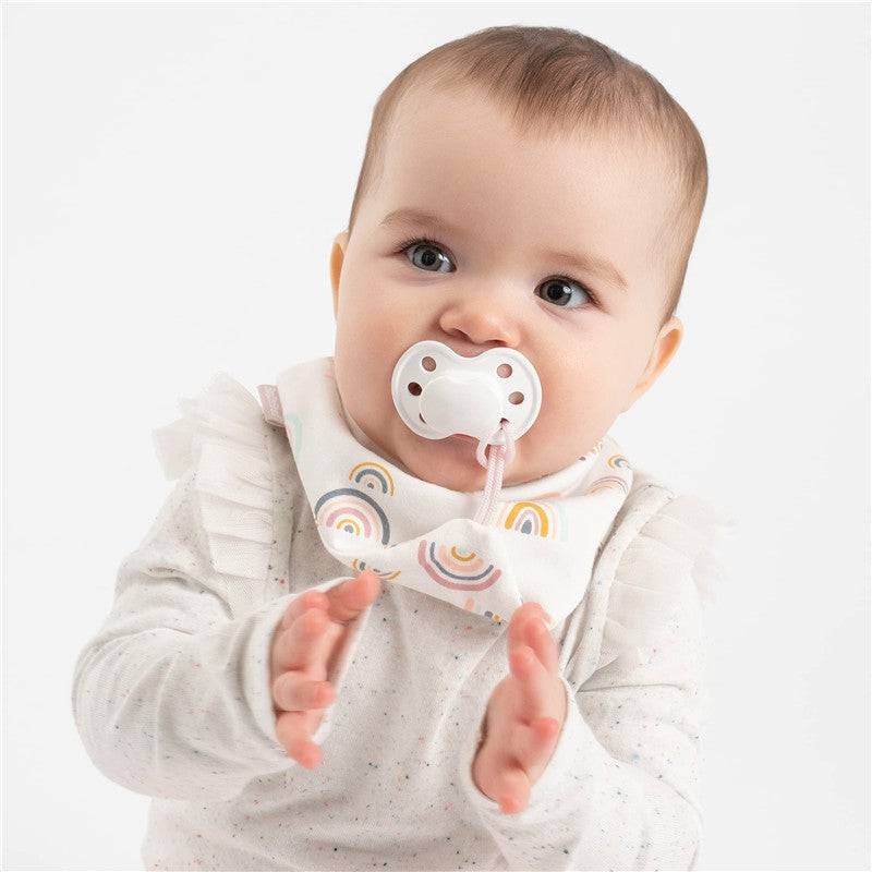 Baby with a pacifier wearing a pink rainbow-patterned bandana bib, clapping hands, smiling.