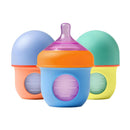 Three colorful Boon Nursh silicone baby bottles (4 oz) in orange, blue, and green, designed for infant feeding.