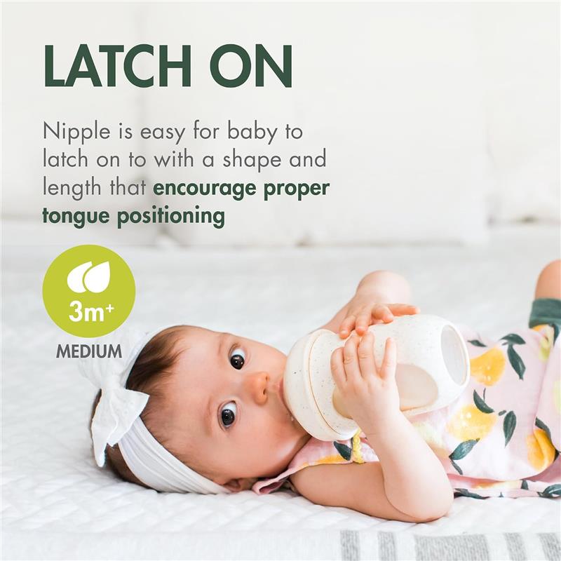 8 oz Boon Nursh silicone baby bottle in speckle green held by a baby, featuring a nipple designed for easy latching and proper tongue positioning.