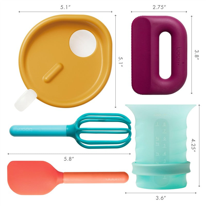 Toddler food prep set featuring a yellow mixing bowl lid, purple grip, aqua measuring cup, turquoise whisk, and orange spatula.