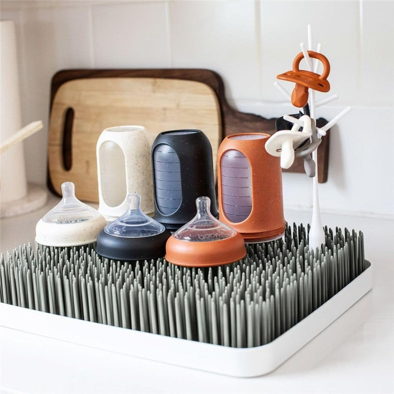 Countertop drying rack with gray and white design, holding various baby bottles and accessories in an organized manner.