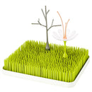 Boon LAWN Drying Rack features green grass-like spikes with a gray twig and a white flower stem for drying bottles and accessories.