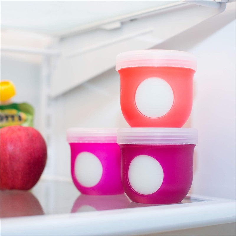 Boon NURSH Storage Caps 3-Pack displayed in a refrigerator, featuring colorful silicone lids in pink and red with white circles.