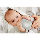 Baby holding a light gray Boon NURSH 4 oz silicone pouch bottle while being cradled in a cozy blanket.