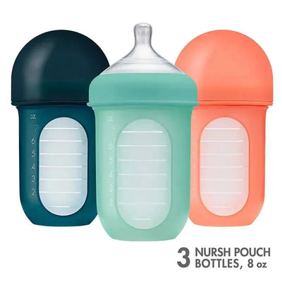 Three 8 oz. silicone baby bottles in mint, cantaloupe, and navy colors, featuring measurement markings on the sides.