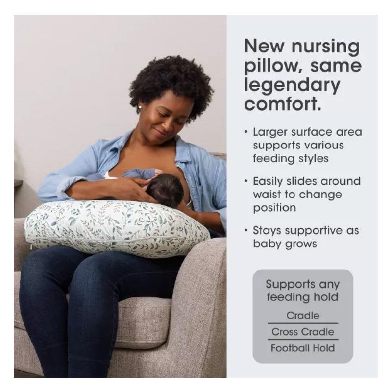 Boppy Nursing Pillow in beige foliage pattern, supporting a mother nursing her baby, features details on versatility and comfort.
