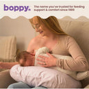 Boppy Nursing Pillow in Blush Butterflies design, featuring a mother breastfeeding her baby comfortably while seated.