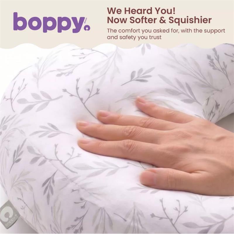Boppy Nursing Pillow in Blush Butterflies with a hand resting on it, showcasing its soft, floral-patterned cover.
