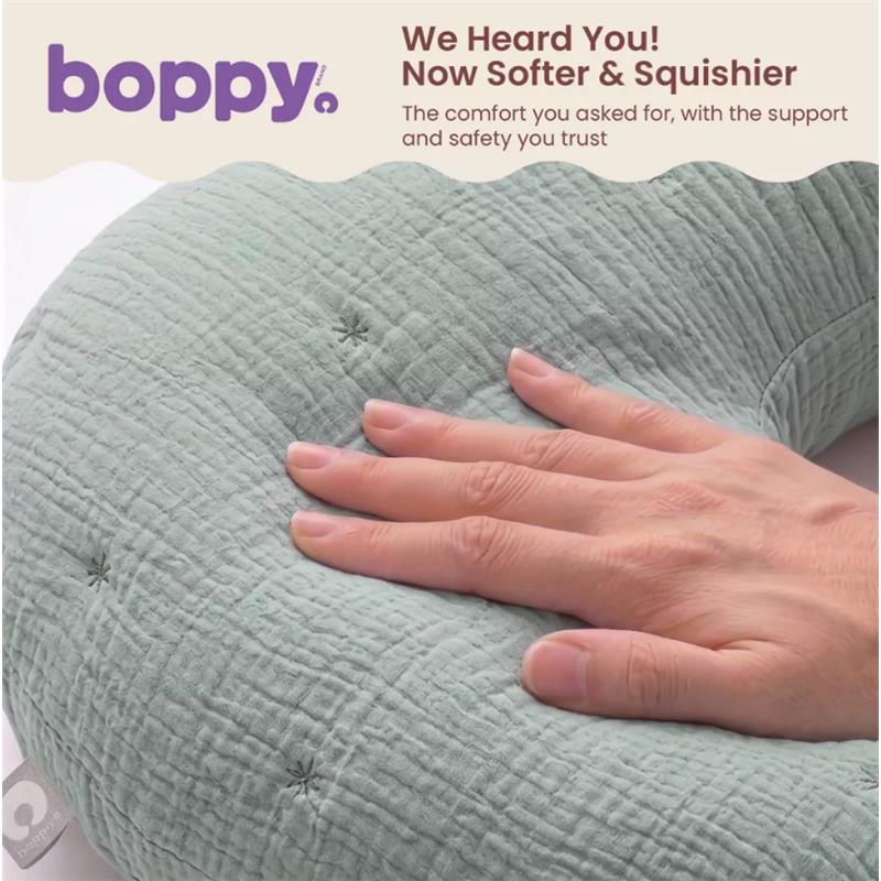 Boppy Nursing Pillow Luxe in Chestnut Muslin, featuring a soft, textured surface, with a hand resting on it.