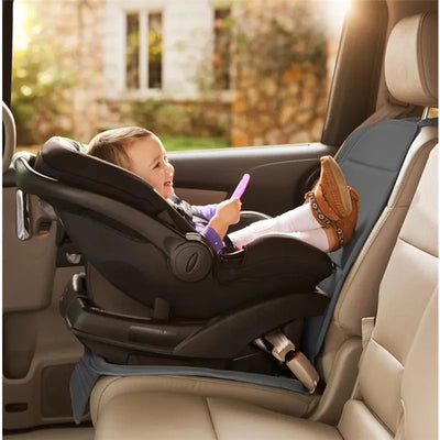 Child in a car seat protector smiling while holding a pink toy, with the seat protector visible on the car seat.
