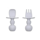 Gray silicone Chewtensils by Bumkins, including a fork and a spoon, designed for toddlers to encourage self-feeding.