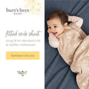 Good Night Sky organic cotton crib sheets set displayed with a smiling baby on a blue mattress, featuring floral designs.