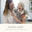 A smiling baby in a gray hooded robe is held by a woman, showcasing soft, 100% organic cotton fabric.