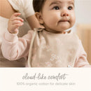 Baby wearing a beige bib with floral patterns, showcasing its 100% organic cotton material for comfort.
