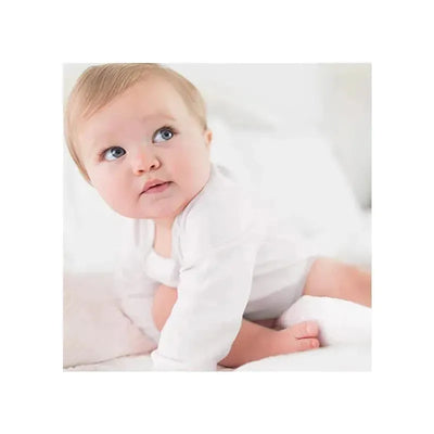 Baby wearing a white long sleeve bodysuit, looking curiously over shoulder while sitting on a soft blanket.
