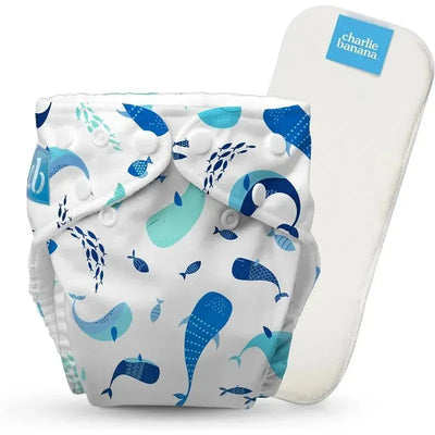 Reusable cloth diaper by Charlie Banana featuring a whale pattern on a white background, adjustable one size with an insert.