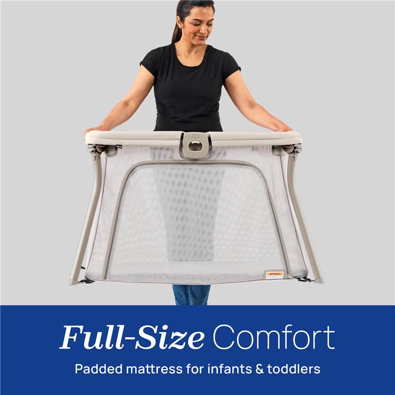Chicco Alfa Lite Portable Playard being held by a woman, featuring a mesh design and a padded mattress for infants and toddlers.