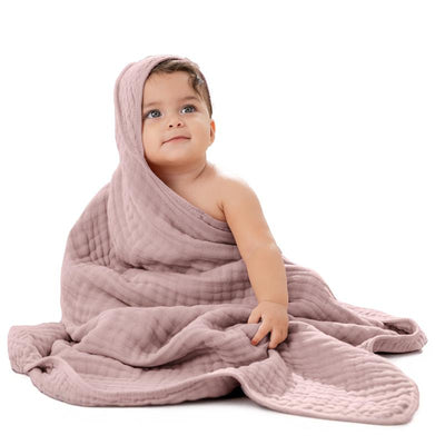 Hooded mauve baby towel draped over a sitting baby, highlighting its soft texture and cozy design.