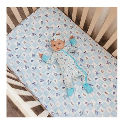 Premium crib sheet featuring Monsters Inc. characters, with a baby in a cozy outfit lying on it.
