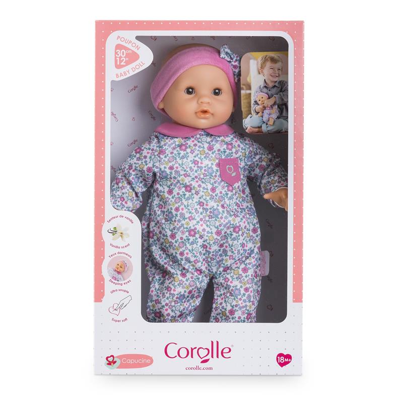 Soft-bodied Corolle doll Bébé Calin Capucine with sleeping eyes, floral outfit, and vanilla scent, packaged in a colorful box.