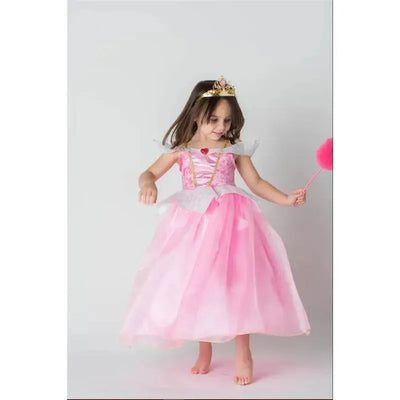 A young girl twirls in a pink Disney Sleeping Cutie dress with a heart and a gold crown, holding a pink wand.
