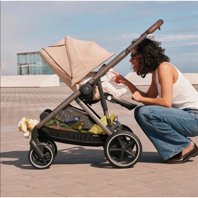 Cybex EGazelle S stroller with taupe frame and chocolate brown seat; a woman interacts with a baby in the stroller.