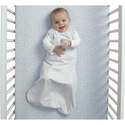 Baby lying in a crib wearing a Delta babyGap TrueSleep Sleep Sack with built-in swaddle, smiling and looking at the camera.
