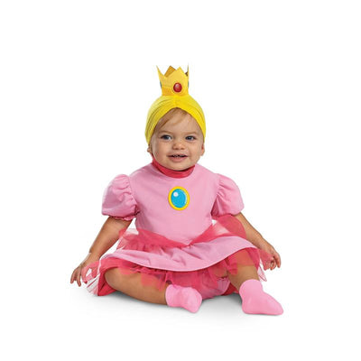 Infant in a pink Princess Peach costume with a crown and yellow headband, smiling while sitting on the floor.