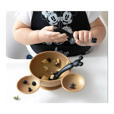 Silicone dipping spoons in the shape of Mickey Mouse used by a child with a bowl of food.