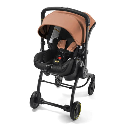 Doona X Infant Car Seat in terracotta color, attached to a latch base, featuring a protective canopy and black seating.