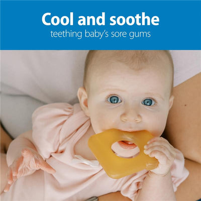 Baby with blue eyes biting a water-filled teether shaped like avocado toast, wearing a pink outfit, soothing sore gums.