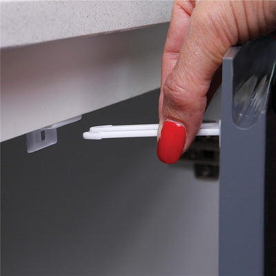 Dreambaby Twin Pin Latches in white being installed on a cabinet by a hand with red nail polish.