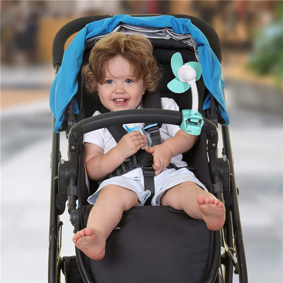 A smiling child sits in a stroller with a turquoise Dreambaby EZY-Fit Clip-On Fan attached, providing a cool breeze.
