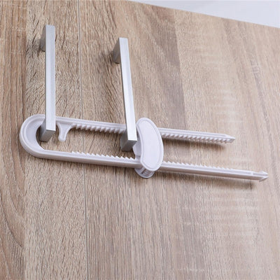 Sliding locks in white with a catch, designed for securing cabinets or doors, mounted on a wooden surface.