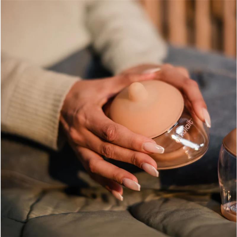 Clear silicone nipple in hand, part of the Emulait Anatomy Bottle, designed for feeding. Nipple color is fair, shape 5.