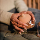 Clear silicone nipple in hand, part of the Emulait Anatomy Bottle, designed for feeding. Nipple color is fair, shape 5.