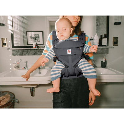 Ergobaby Omni Classic Baby Carrier holding a baby, with a caregiver in a bathroom setting.