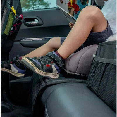 Child sitting in a car with their feet on the Ezimoov Ezi Seat Protector, reading a book.